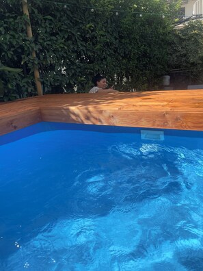 Une piscine avec une terrasse en bois et une personne debout au bord.