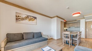 A modern living room with a sofa, a coffee table, and a dining area with chairs and a table.