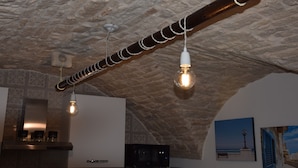 Un interior rústico con techo de piedra a la vista, una viga de madera e iluminación colgante.