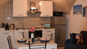 Cocina compacta con mesa, sillas y refrigerador.