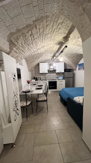 Cozy retreat with a unique arched ceiling, dining area, kitchenette, and single bed.