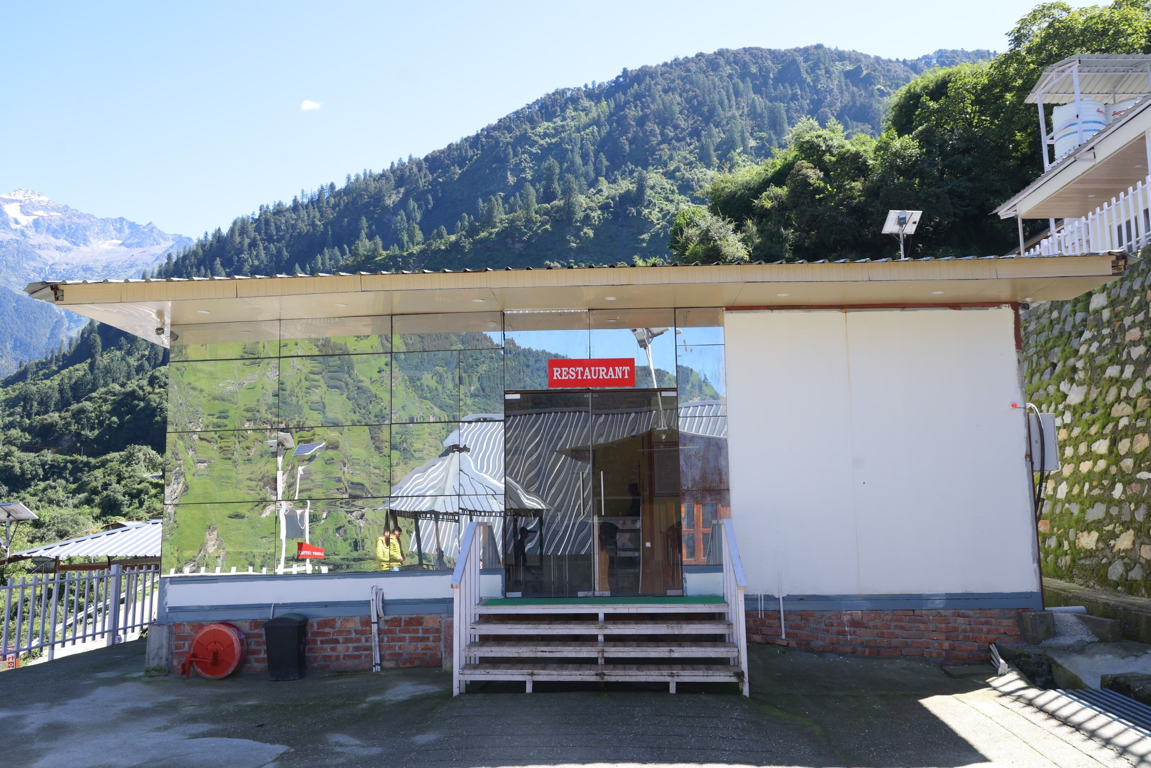 Un restaurante con las montañas al fondo, cielo despejado y vistas al valle.