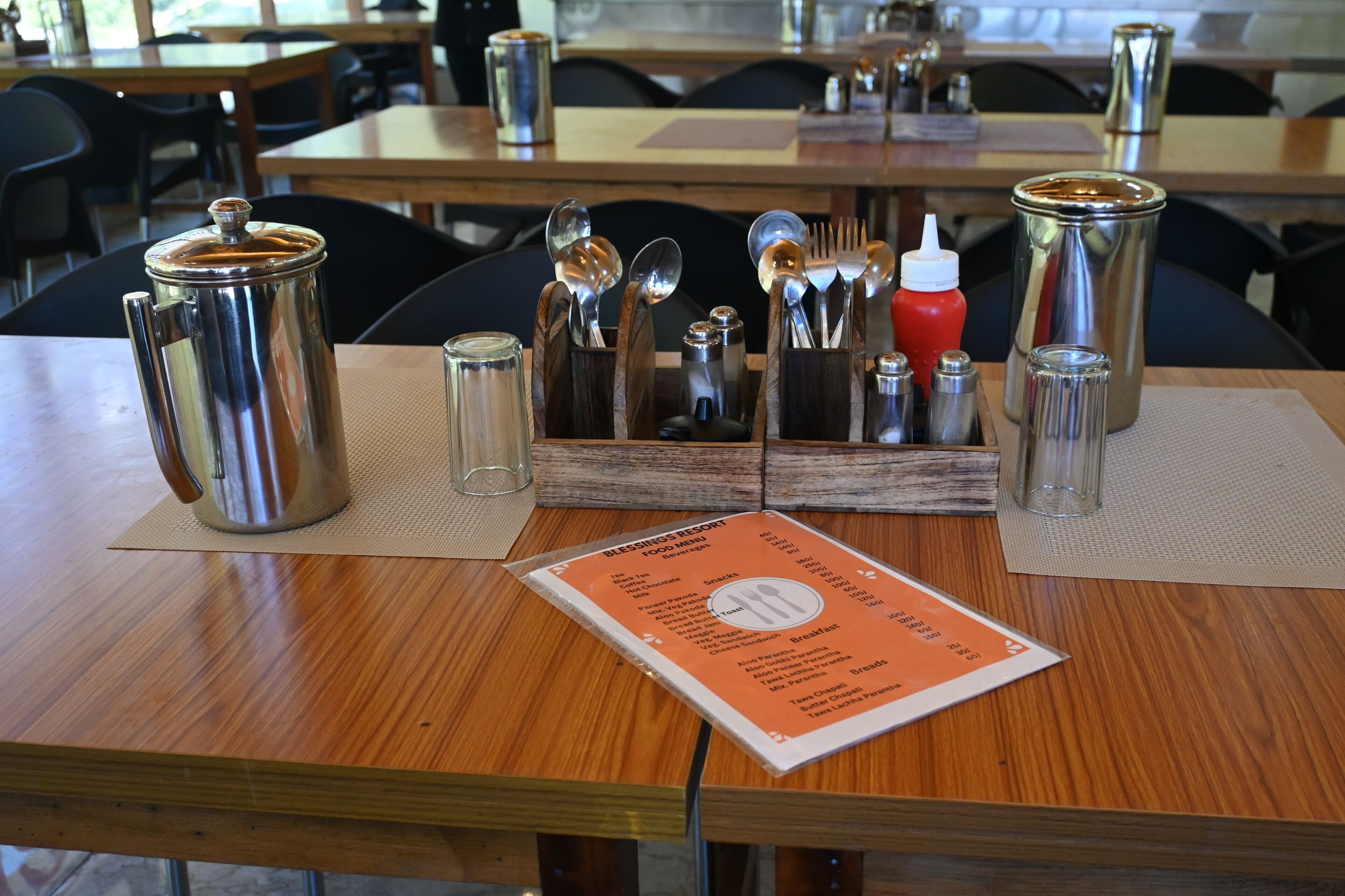 Une table de restaurant avec un menu, une cafetière et un présentoir à condiments.