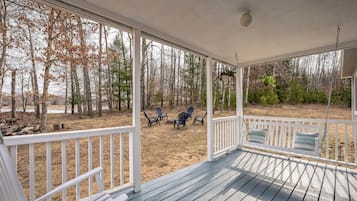 Relax on the covered porch with a swing seat and Adirondack chairs, taking in the serene natural surroundings.