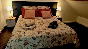 A hotel room with a bed, two nightstands, two lamps, and a wooden beam ceiling. - La Faran'dole - The cosy cocoon on the edge of the greenway. (Dole)