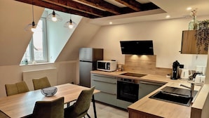 A modern kitchen with a wooden ceiling, a built-in microwave, a refrigerator, and a sink. - La Faran'dole - The cosy cocoon on the edge of the greenway. (Dole)