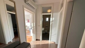 A hallway with a bench, a door leading to a bathroom, and a view into another room. - Big Sea View apartment within walking distance of the old town, beach and shops (Krk)