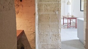 Ein Innenraum mit Steinwänden, Fliesenboden, einem Tisch und einer Hängelampe.
