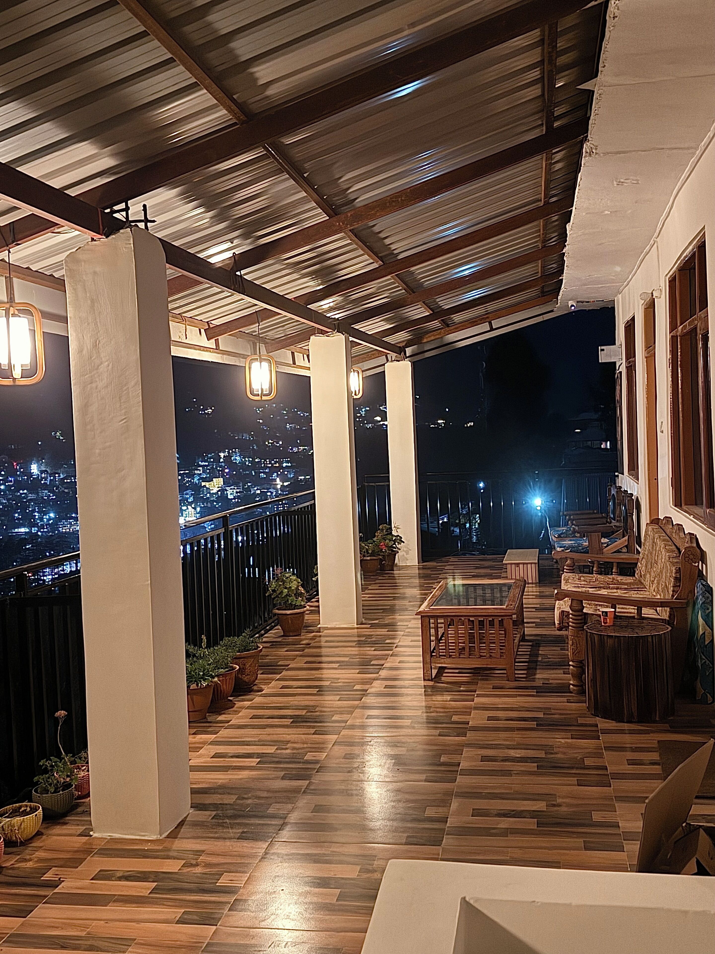 Espaço ao ar livre coberto com piso de madeira, plantas em vasos e áreas de estar.