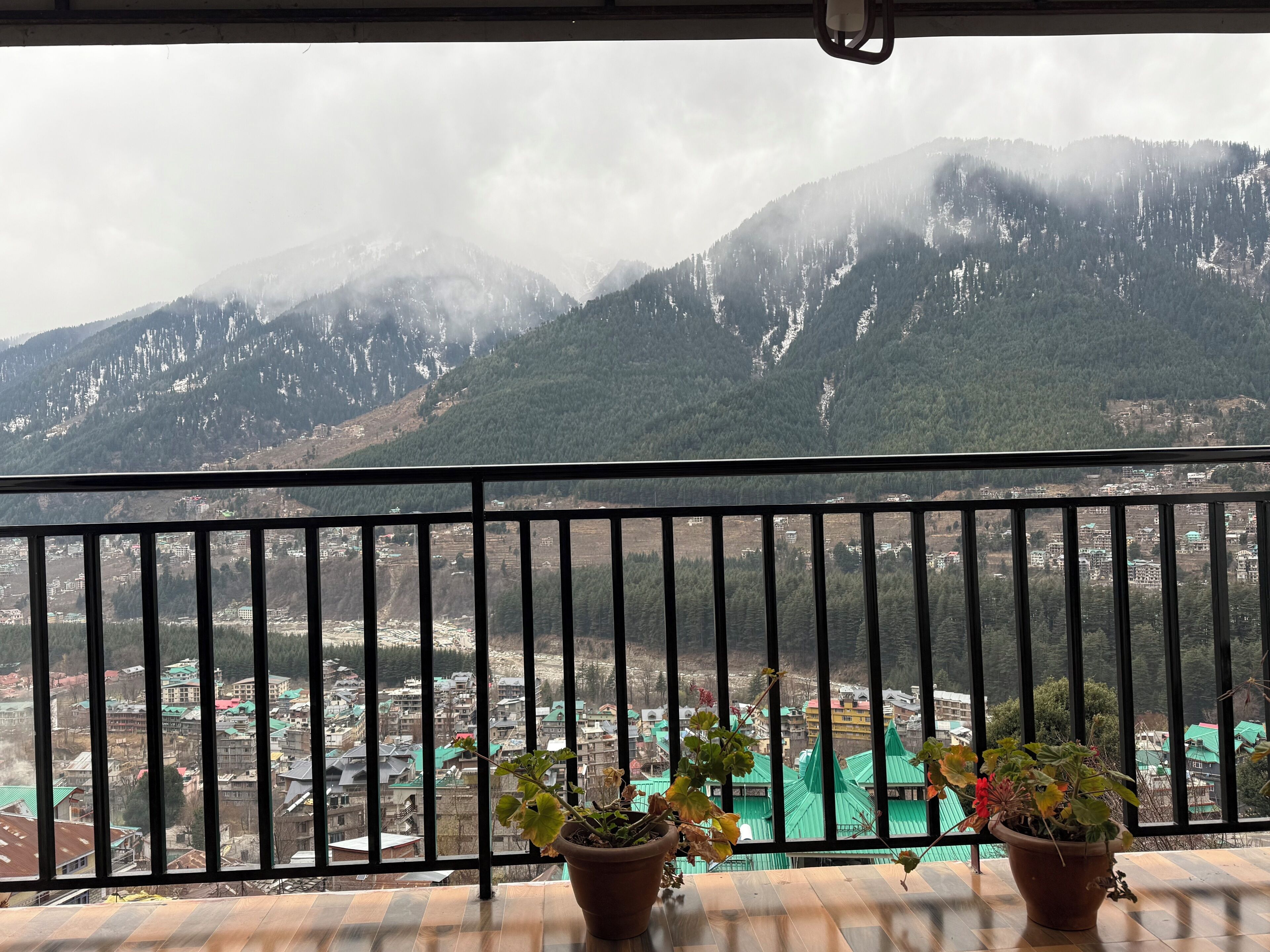 A balcony with a view of a mountainous landscape and a town below.