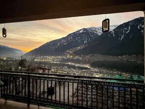 A balcony with a view of a town and mountains during sunset. - Aura by RA Manali - Mountain View (Manali)