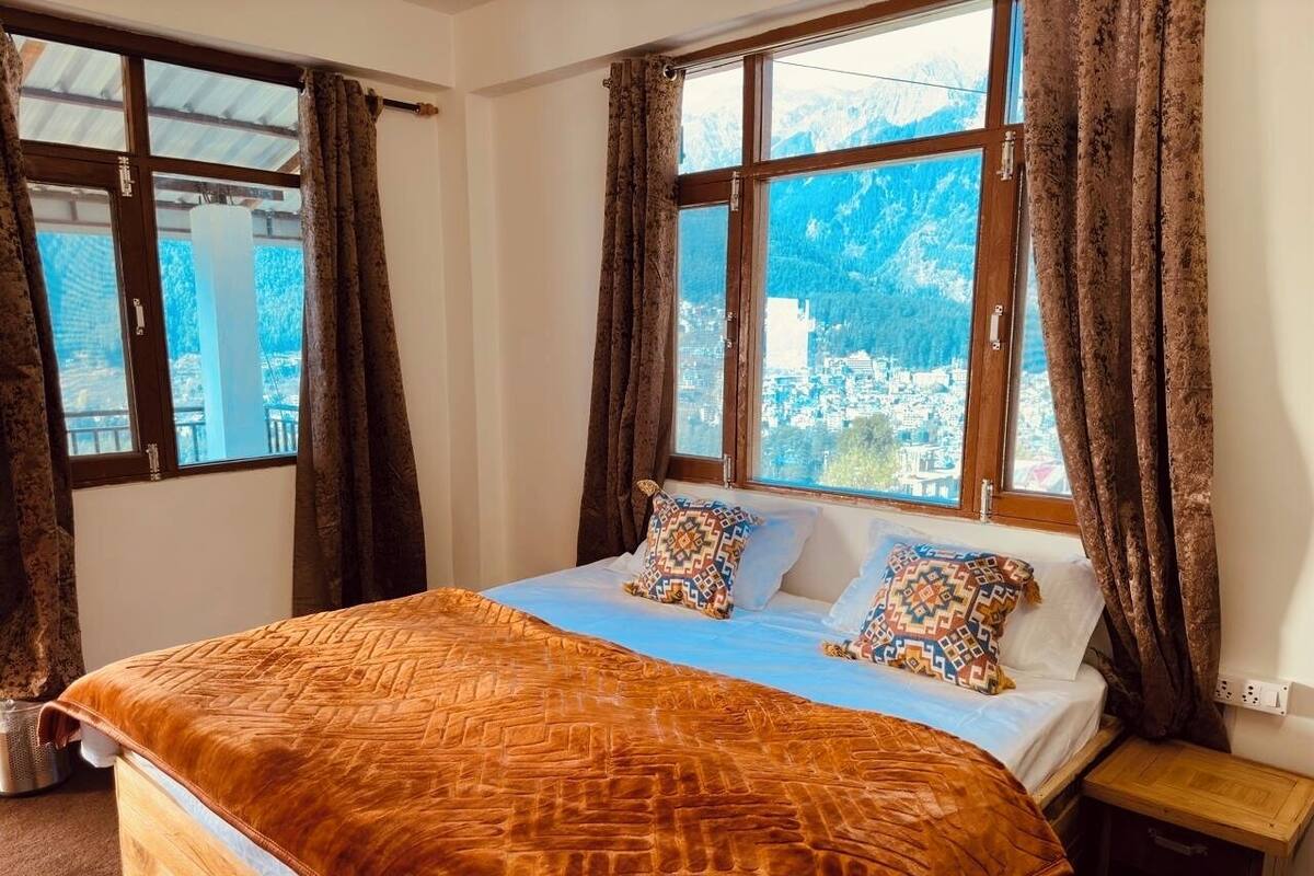 Ein Schlafzimmer mit einem großen Bett, zwei Kissen, einem Nachttisch und einem Fenster mit Vorhängen.