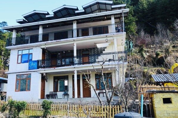 A two-story building with balconies, a front porch, and a small attached structure.