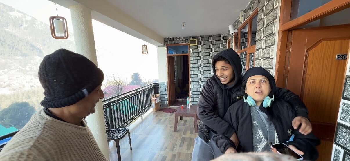 Un balcon avec vue sur les montagnes, une porte en bois portant le numéro 20 et un mur orné de motifs.