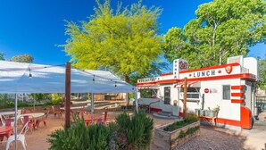 A small outdoor dining area with tables and chairs, a covered seating area, and a building labeled "O's Diner" with signs for breakfast and lunch.