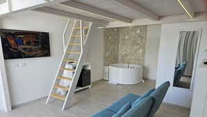 Una sala de estar moderna con un sofá azul, una mesa redonda blanca, una pared de piedra y una escalera de madera.