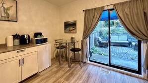 Una cocina compacta con comedor, microondas, cafetera y ventana con cortinas.
