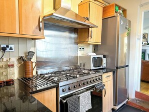 Une cuisine équipée d’appareils électroménagers en acier inoxydable, de meubles de rangement en bois et d’un four à micro-ondes.