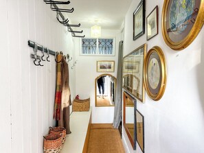 A hallway with a coat rack, a mirror, and framed pictures on the walls.