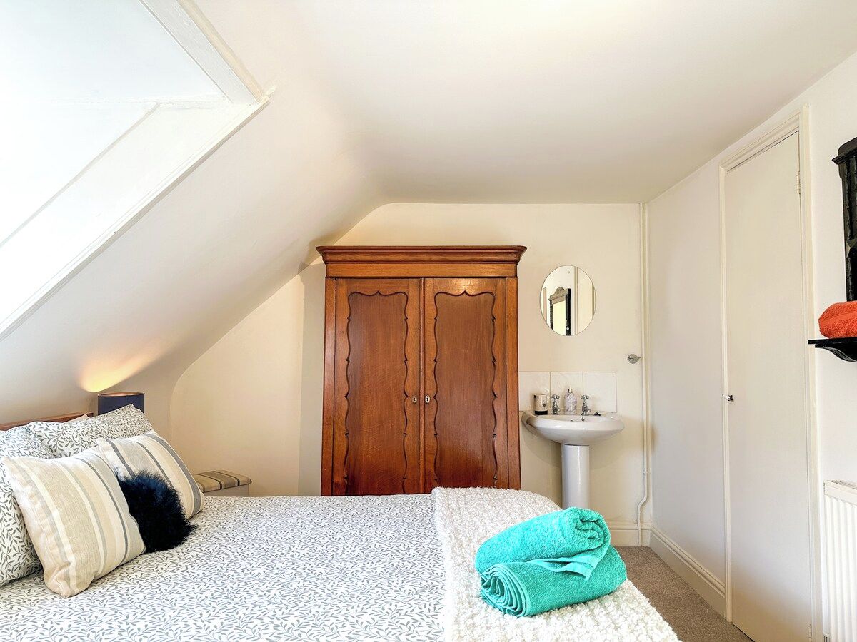 A bedroom with a bed, a wardrobe, a bedside table, a mirror, and a radiator.