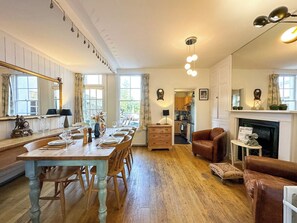 Un espace repas comprenant une table et des chaises en bois, une cheminée et un coin salon confortable avec des canapés en cuir.