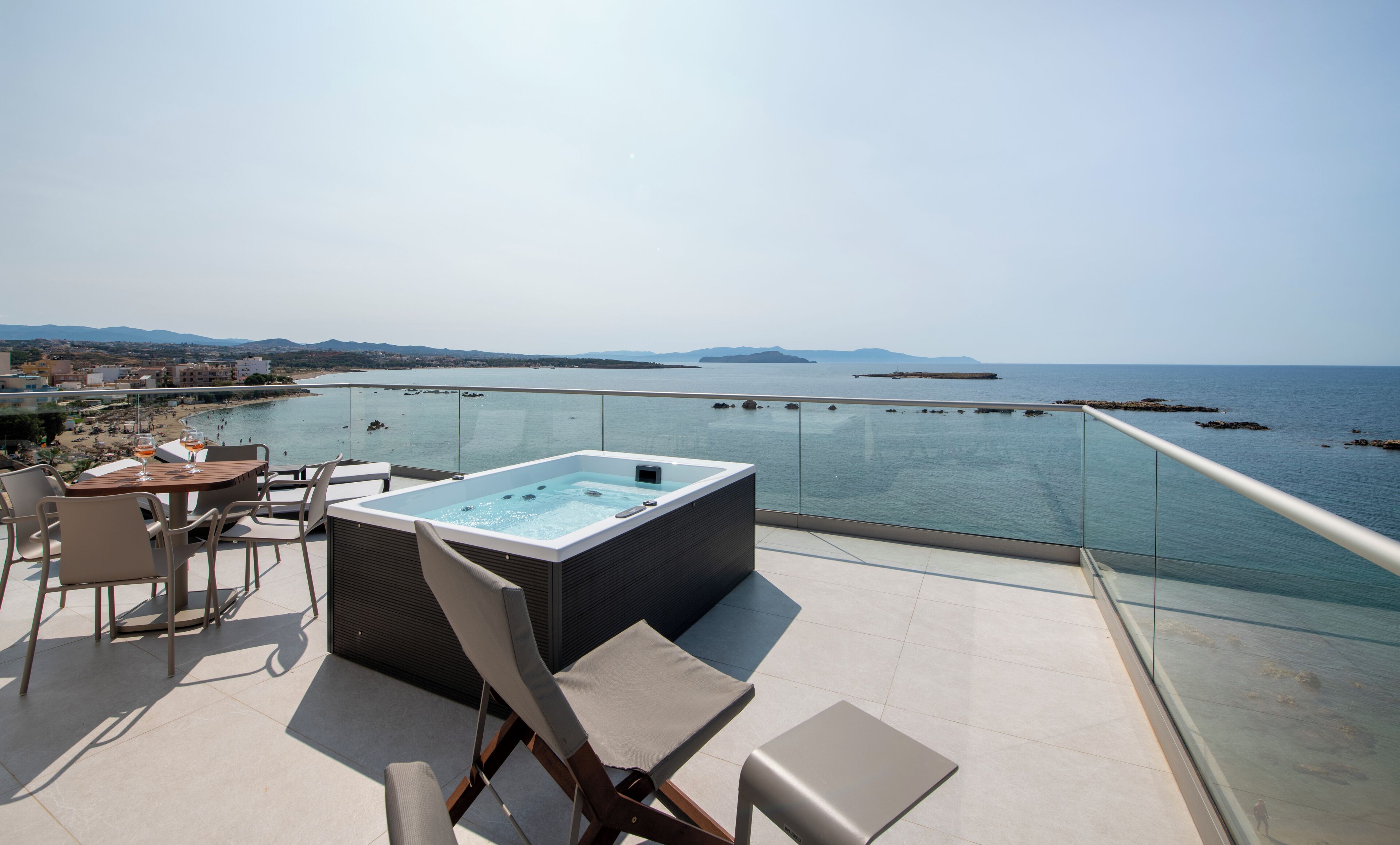 Una terraza en la azotea con jacuzzi, zona de estar y vistas al mar.