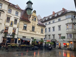 A historic building with ornate architectural details, a clock tower, and a café with outdoor seating. - Carillon by BestChoice - Parking Option (Graz)