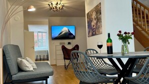 A modern living room with a sofa, dining table, chairs, a TV, and a chandelier. - Carillon by BestChoice  - Parking Option (Graz)