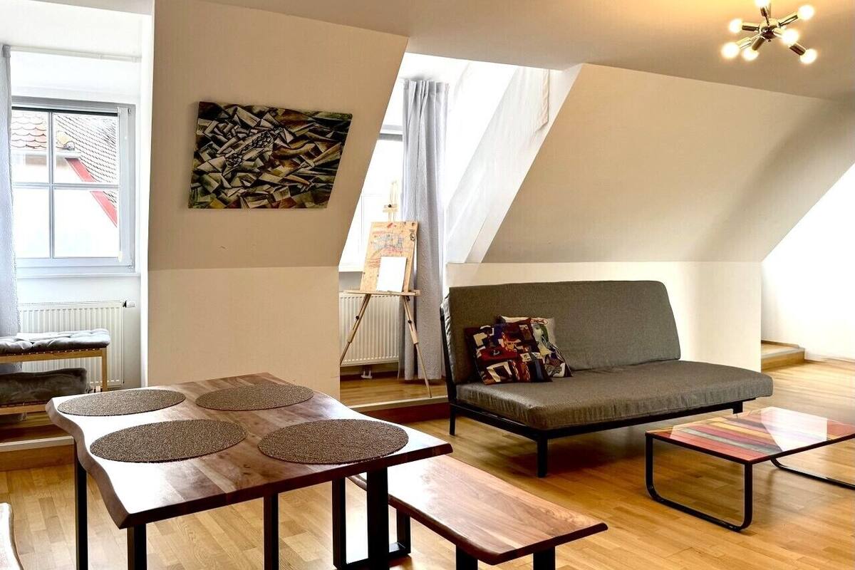 Un salón estilo loft con techo alto, un sofá, una mesa de centro y un cuadro en la pared.
