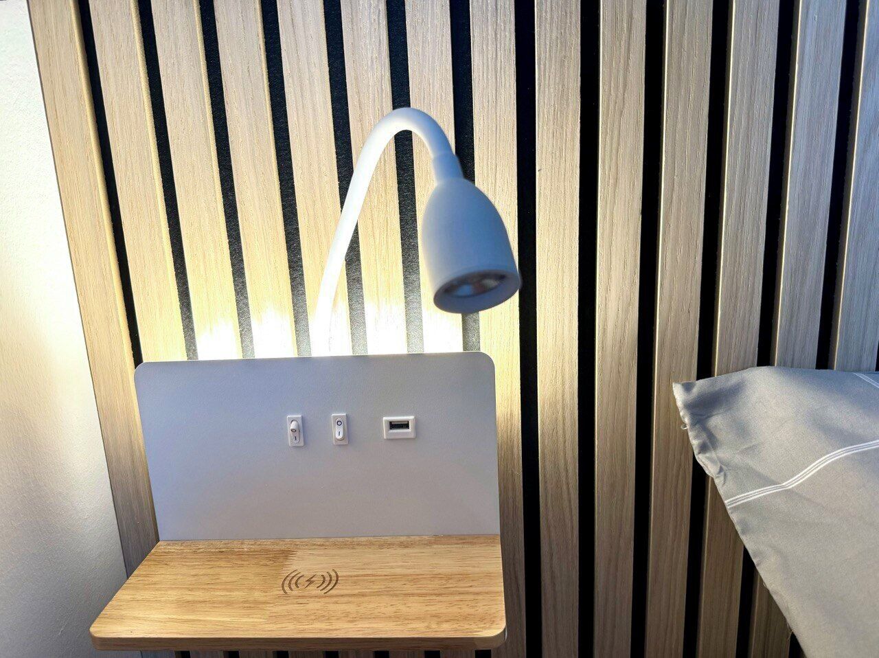 Un bureau moderne et minimaliste doté d’une station de recharge intégrée et d’une élégante lampe blanche.