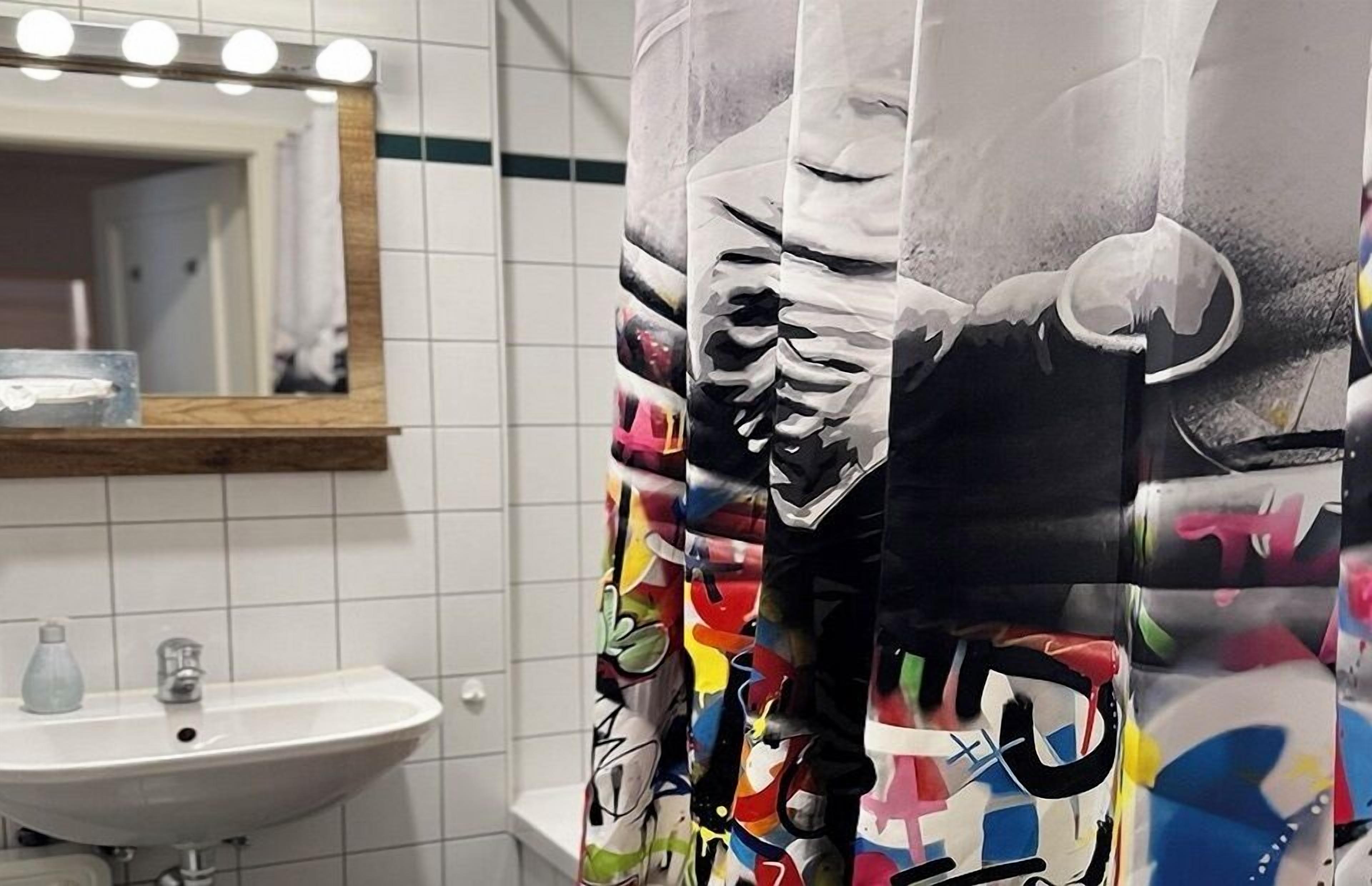 Une salle de bain avec un lavabo blanc, un miroir et des murs carrelés.
