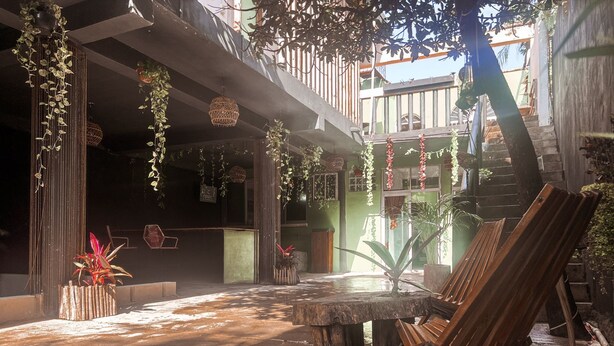 An outdoor courtyard with a concrete floor, a wooden table, and a wooden easel. - Varuna Home (Tulum)
