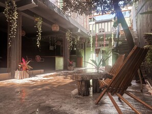 An outdoor courtyard with a concrete floor, a wooden table, and a wooden easel. - Varuna Home (Tulum)