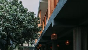A building with a modern design, featuring a balcony with wooden railings and hanging lanterns. - Varuna Home (Tulum)