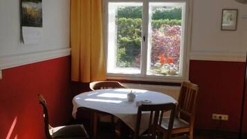 Ein Essbereich mit Tisch und Stühlen, einem Fenster mit Vorhängen sowie Bildern an der Wand.