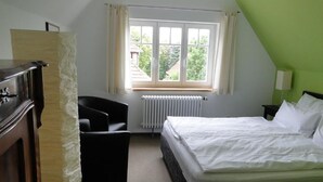A bedroom with a bed, a desk, a chair, a radiator, and a window with curtains. - Pension Villa am Burgberg (Waltershausen)