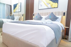A hotel room with a large bed, a bedside table, and a nightstand. - Bloomfields Lovely 1BHK Azizi Riviera (Dubai)
