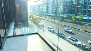 A modern hotel room with a large window overlooking a busy street and high-rise buildings.