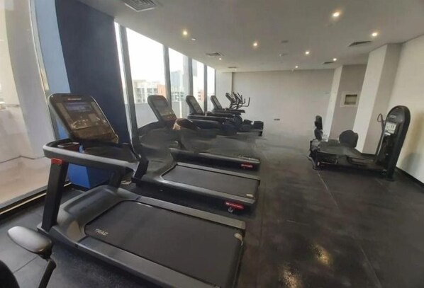 A gym with treadmills and exercise bikes, large windows, and a modern design.