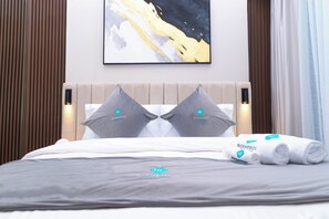 Ett hotellrum med en säng, kuddar, ett täcke och en handduk.