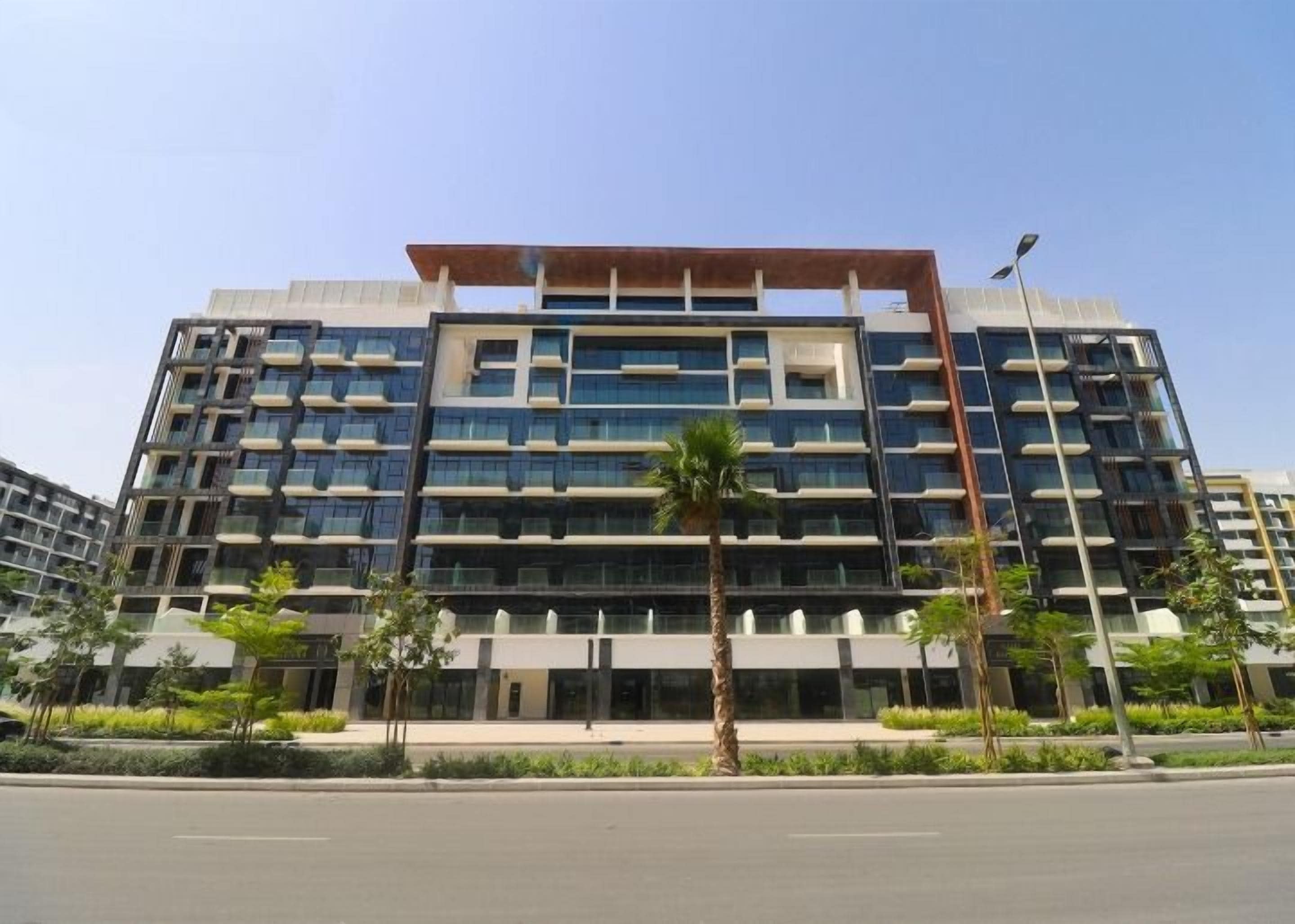 A multi-story building with a modern architectural design, featuring a flat roof and a series of balconies.