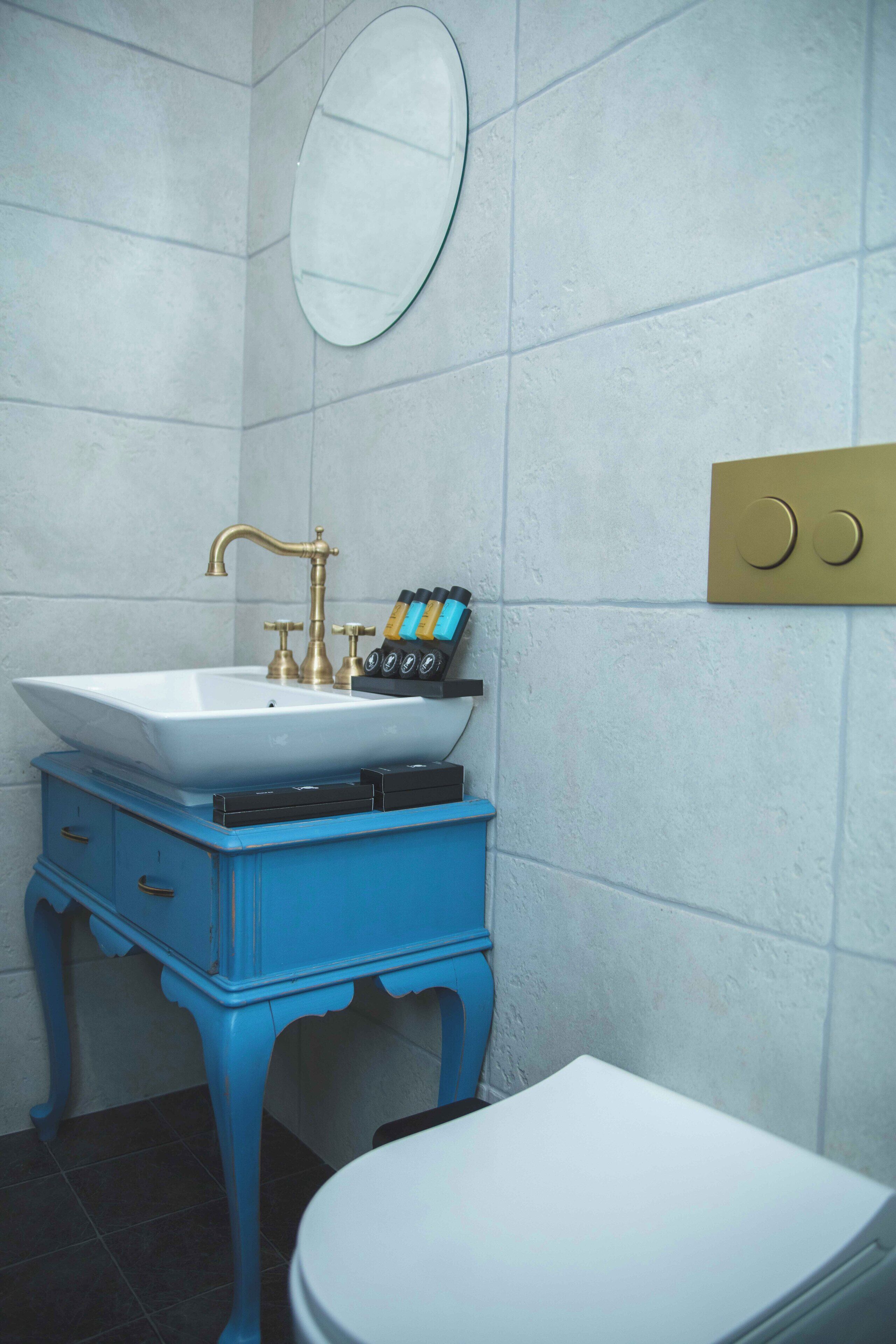 A bathroom with a white sink, blue vanity, and a white toilet.