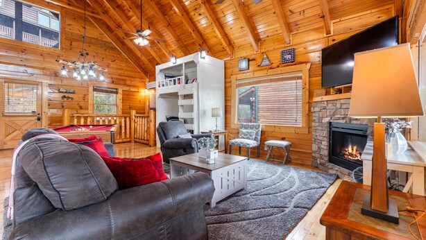 A cozy cabin interior with a fireplace, wooden walls, a pool table, and a comfortable seating area. - Moonlight Ridge! Mtn views! Hot tub! Pool! (Sevierville)