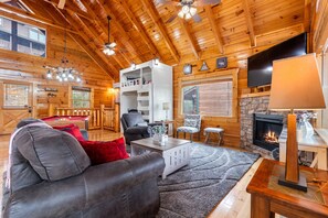 A cozy cabin interior with a fireplace, wooden walls, a pool table, and a comfortable seating area. - Moonlight Ridge! Mtn views! Hot tub! Pool! (Sevierville)