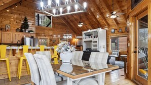 A wooden cabin interior with a dining area, kitchen, and living space. - Moonlight Ridge! Mtn views! Hot tub! Pool! (Sevierville)