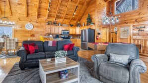 A cozy log cabin interior with a living room, dining area, and kitchen. - Moonlight Ridge! Mtn views! Hot tub! Pool! (Sevierville)