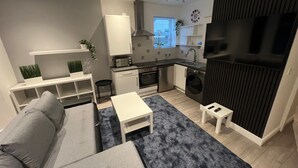 A modern living room with a grey sofa, a small white table, and a blue rug.