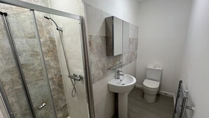 A bathroom with a glass-enclosed shower, a pedestal sink, and a toilet.