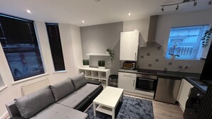 A modern living room with a grey sofa, a small white table, and a blue rug.