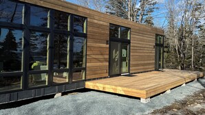 A modern wooden cabin with large windows and a wooden deck.